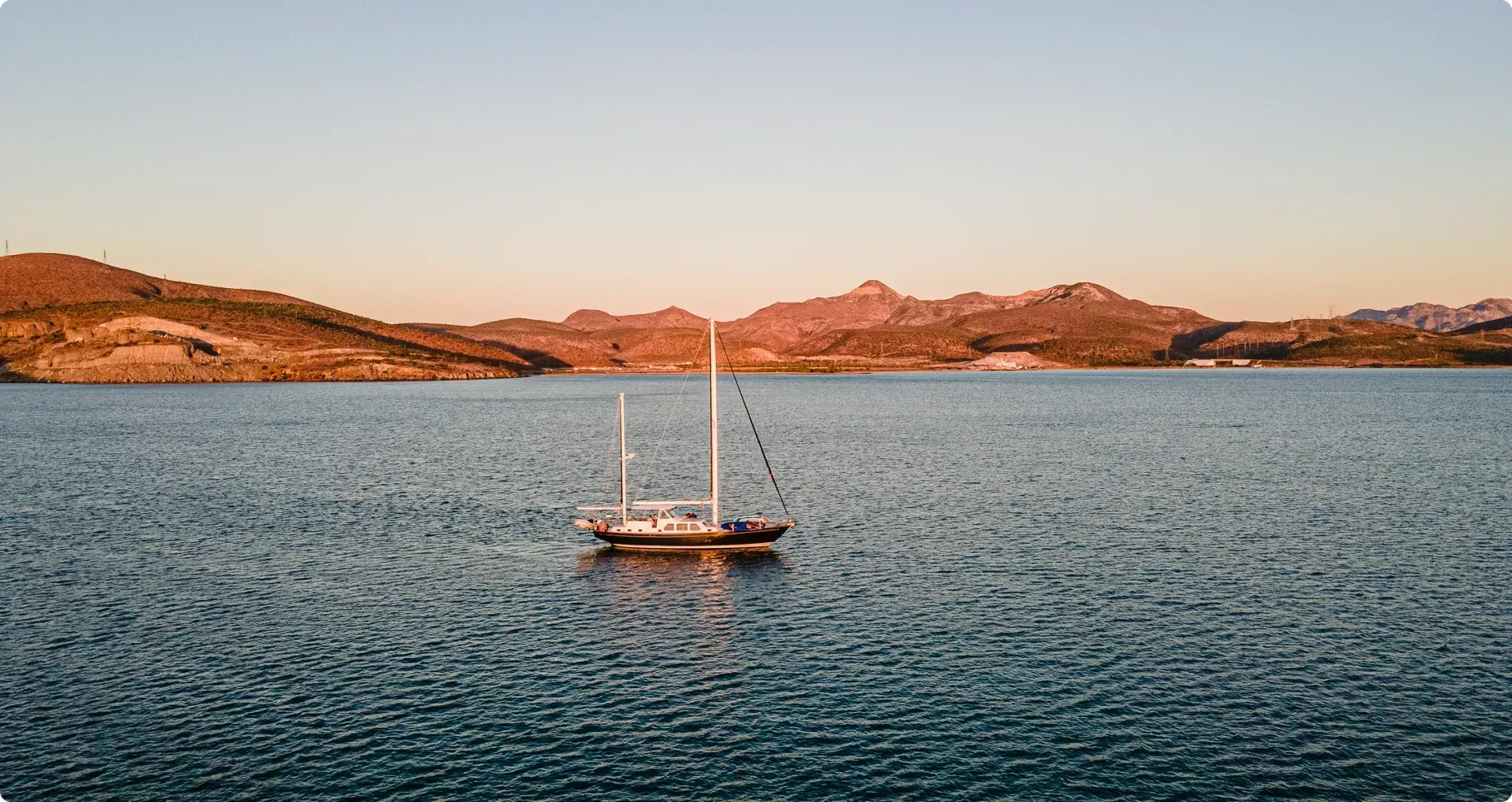 sailbioat in front of island at sunset